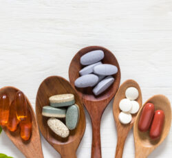 Variety,of,vitamin,pills,in,wooden,spoon,on,white,background